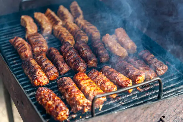 small Romanian minced meatrolls called mici or mititei, similar to serbian cevapi, fresh balkan skinless sausages, cooked outside on the barbecue