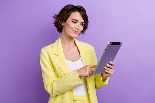 Portrait of pretty woman wear lime glamour suit browsing her tablet customer support online assistant isolated on purple color background.