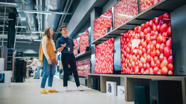 istock Beautiful Client Engaging in Dialogue with Retail Electronics Shop Consultant. Female Seeks Smart, Internet-Connected TV. Customer Exploring Advanced Television Choices in a Modern Retail Store 2065386699