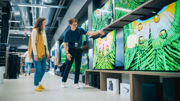 istock Beautiful Client Engaging in Dialogue with Retail Electronics Shop Consultant. Female Seeks Smart, Internet-Connected TV. Customer Exploring Advanced Television Choices in Modern Retail Store 2065387231