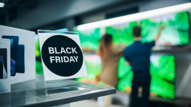 close up of a black friday sale sign in a home electronics department store with a range of modern smart tv sets. shoppers explore discounted home appliances in a busy retail storefront showroom - department store clothing showroom people ストックフォトと画像