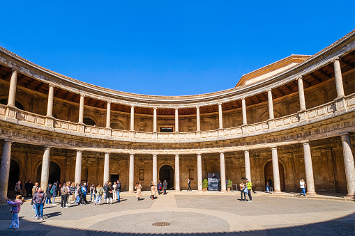Tourists visiting the Patio of the Palace of Charles V, a Renaissance building whose construction began in 1527 inside the Alhambra of Granada, a monumental complex that is the main landmark of the city.
