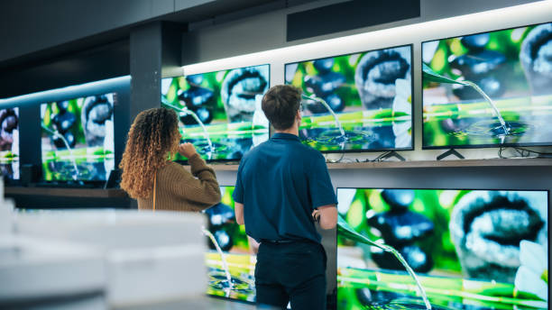 female client engaging having a conversation with a retail electronics shop consultant. female seeks smart, internet-connected tv. customer exploring advanced television choices in modern retail store - department store clothing showroom people ストックフォトと画像