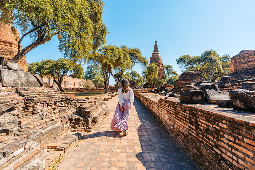 Rear-view of a young woman walking at Wat Ratchaburana in Ayutthaya historical park in Ayutthaya in Thailand.