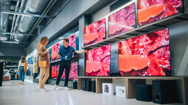 istock Hispanic Woman Having a Conversation with Home Electronics Store Associate. Young Multiethnic Customer Pursues Cutting-Edge TV Technology. Shopper Examining Modern Television Selection in a Showroom 2065393334