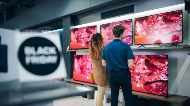 modern retail electronics store on black friday sale event. female looking to buy a smart flat-screen television set. customers explore discounted tvs, guided by attentive sales team - department store clothing showroom people ストックフォトと画像