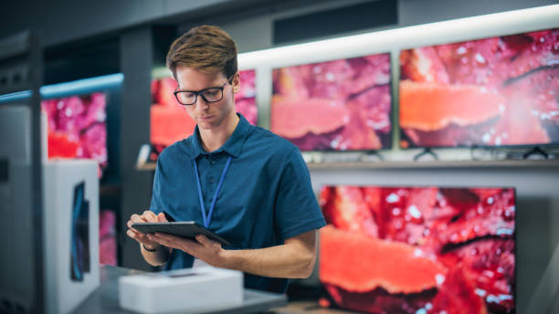 istock Young Productive Salesperson in Home Electronics Store Working on Tablet Computer. Professional Staff Member Using Software to Monitor Inventory, Track Device Sales, and Provide Customer Service 2065409790