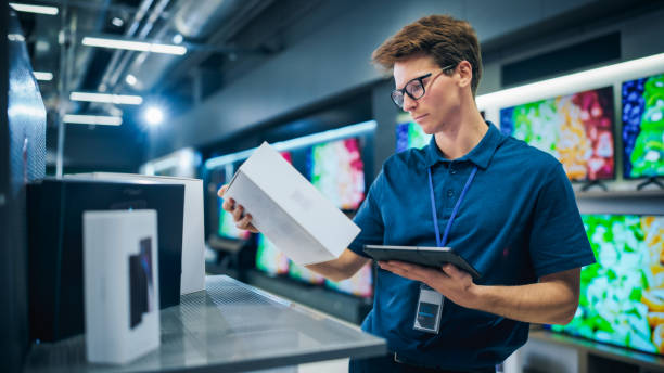istock Young Sales Manager in Home Electronics Store Expertly Manages Operations Using Tablet Computer. Professional Oversees Smartphone Inventory and Product Updates with Technological Efficiency 2065410216