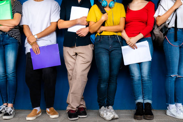 istock Small group of high school students stand leaning against blue wall before class. Back to school. 2065413887