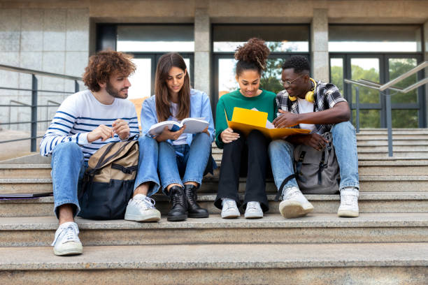 istock Happy diverse university student friends doing homework together sitting on campus steps. 2065414633