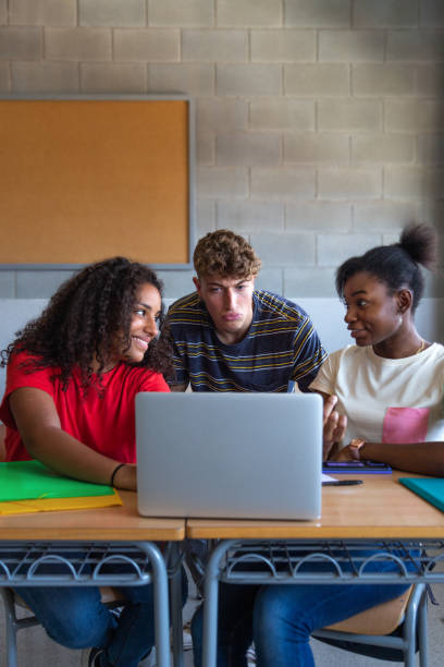 istock Multiracial group of high school students doing homework research together using laptop in class. Vertical image. 2065416755