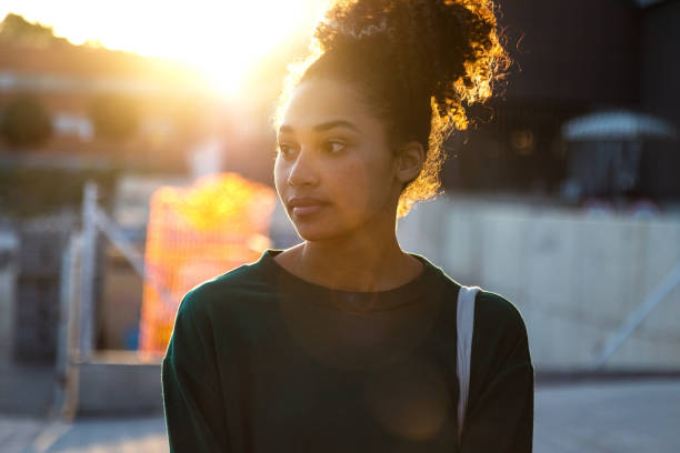 istock Back lit young pensive African American woman outdoors during sunset. 2065417315