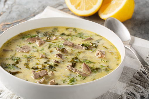 Magiritsa is a Greek soup made from lamb offal, associated with the Easter tradition close-up in a bowl on a marble table. Horizontal