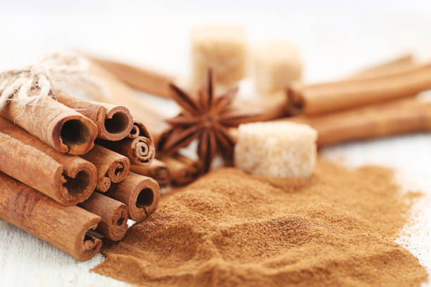 istock Cinnamon powder with sticks and sugar cubes on white wooden background 2065444880