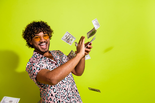 Photo portrait of attractive young man throw banknotes wear trendy pink leopard print clothes isolated on yellow color background.