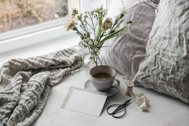 istock Easter composition. Spring still life. Cup of coffee, floral bouquet. Window sill. White tulips, carnation, wax flowers. Blank greeting card mockup. Pillows, old scissors. Scandinavian home, breakfast 2065453900
