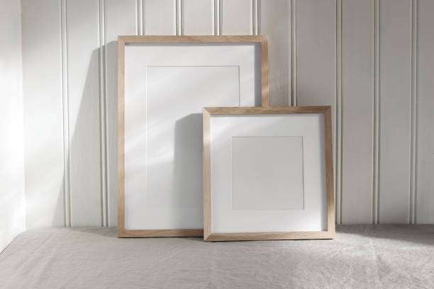 Set of blank vertical and square wooden picture frame mock ups in sunlight. White beadboard wainscot wall paneling background with shadows. Neutral Scandinavian home decor, nordic interior. conjunto de maquetas de marcos de madera verticales y cuadrados en blanco a la luz del sol. fondo de paneles de pared de revestimiento de madera de tablero de cuentas blanco con sombras. decoración neutra escandinava para el hogar. interior nórdico.