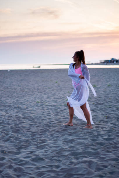 istock Happy woman spins on the beach during sunset 2065454441