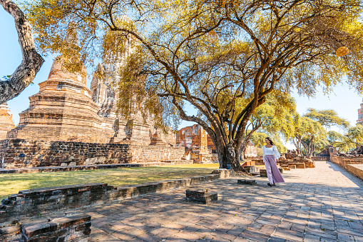 Young woman walking at Wat Ratchaburana in Ayutthaya historical park in Ayutthaya in Thailand.
