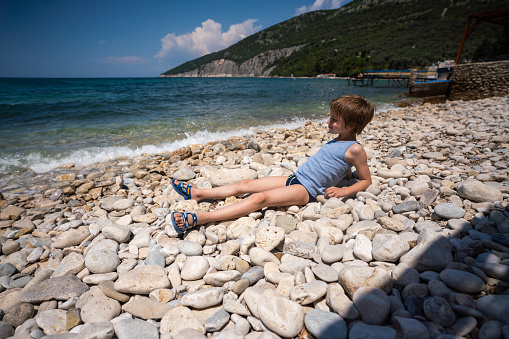 Full length of a happy boy lies on the beach during a summer day