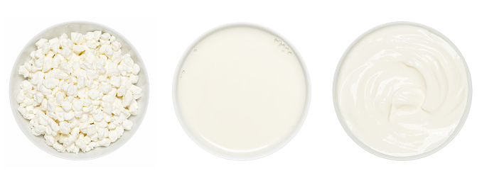 Dairy products in the white plates isolated on white. Cottage cheese, milk and sour cream top view