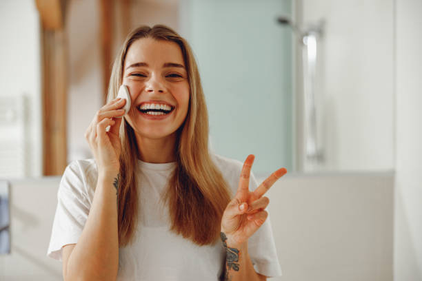 istock Young woman removing makeup with cotton pad standing in bathroom. Home beauty routine 2065484437