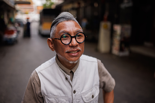 Mature Asian man walking on the street in Bangkok.