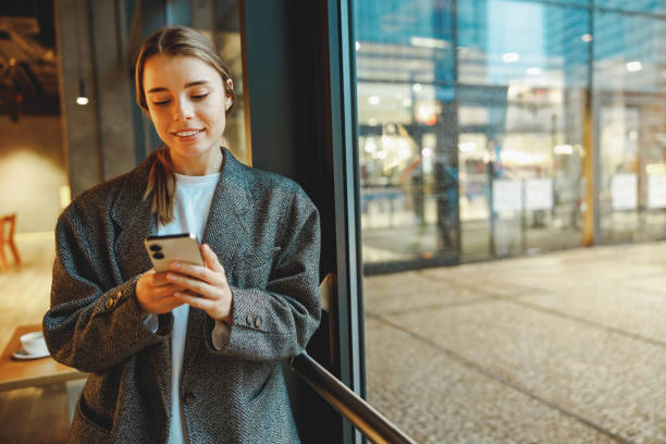 istock Young female entrepreneur is use phone while standing in cafe near window. Distance work concept 2065490998