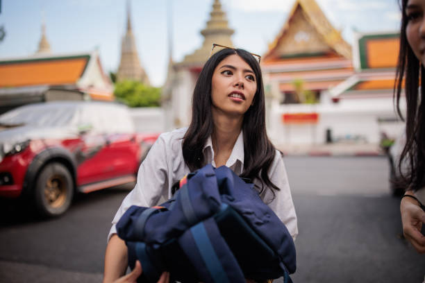 Women tourists with backpacks standing on the street in Bangkok.