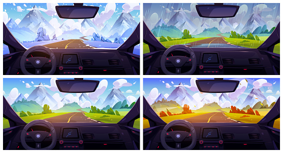 View from car through windshield on road going across meadow to high rocky mountains in for seasons with different weather. Natural landscape from inside via automobile window with navigation panel.