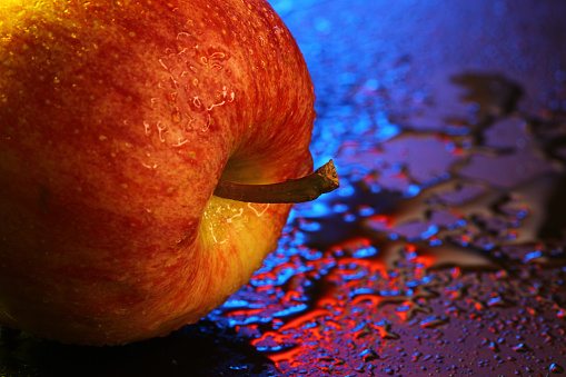 Red backlight apple with water droplets and bokeh