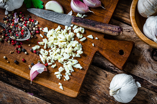 Overhead view of chopped garlic on wooden cutting board