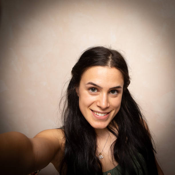 istock smiling young woman taking a self-portrait with beige background 2065532311