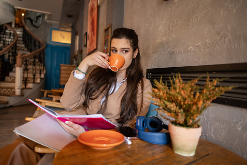 With her mind set on success, a chic student savors her coffee while cramming for her exam in a bustling cafe.
