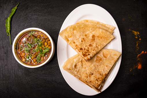 paratha with dal chana or chanay served in dish isolated on dark background top view indian spices, bangladeshi and pakistani food