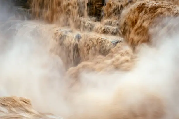 The Hukou Waterfall (simplified Chinese: 壶口瀑布; traditional Chinese: 壺口瀑布; pinyin: Húkǒu Pùbù), is the largest waterfall on the Yellow River, the second largest waterfall in China (after the Huangguoshu Waterfall in Guizhou), and the world's largest yellow waterfall. It is located at the intersection of the provinces of Shanxi and Shaanxi, 165 km (103 mi) to the west of Fenxi County, and 50 km (31 mi) to the east of Yichuan County where the middle reaches of the Yellow River flow through Jinxia Grand Canyon. The width of the waterfall changes with the season, usually 30 metres (98 ft) wide but increasing to 50 m (164 ft) during flood season. It has a height of over 20 m (66 ft). When the Yellow River approaches the Hukou Mountain, blocked by mountains on both sides, its width is abruptly narrowed down to 20–30 m (66–98 ft). The water's velocity increases, and then plunges over a narrow opening on a cliff, forming a waterfall 15 m (49 ft) high and 20 m (66 ft) wide, as if water were pouring down from a huge teapot. Hence it gets the name Hukou (literally, "flask mouth") Waterfall.