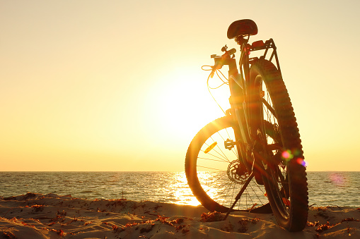 Backlit ebike in silhouette at sunset on the beach