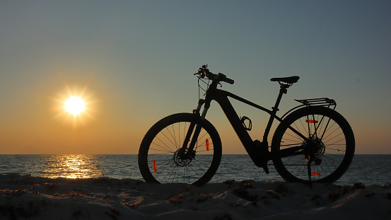 Backlit ebike in silhouette at sunset on the beach