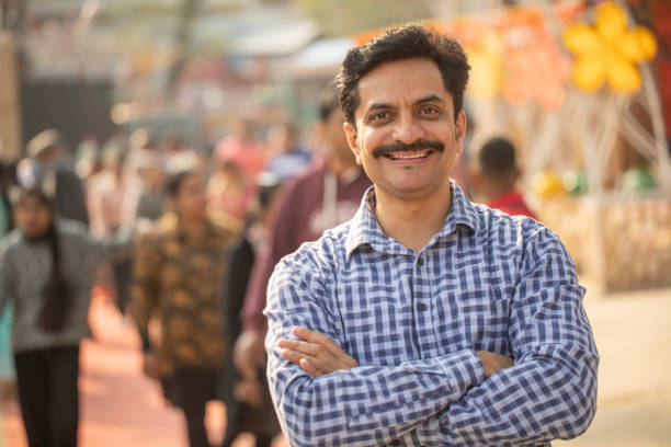 Portrait of smiling mid adult man with arms crossed standing in street market at Surajkund fair