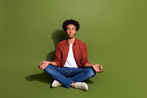 Full length photo of nice young man sit floor meditation lotus pose dressed stylish brown garment isolated on khaki color background.