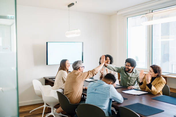 istock A jubilant team in an office setting participates in a group high-five, an expression of their collaborative spirit and shared goals. The open and bright workspace adds to the vibrant energy of their team success. 2065627581