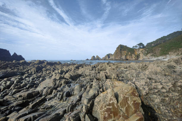 istock a rugged shoreline with jagged rock formations, calm sea waters, and a clear sky with wispy clouds. Its a serene and natural setting 2065629164