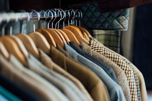 A variety of suit jackets hanging up on a clothes rack for sale in a vintage clothing store in Durham, North East England. The main focus is the shoulders of the jackets and their coat hangers.