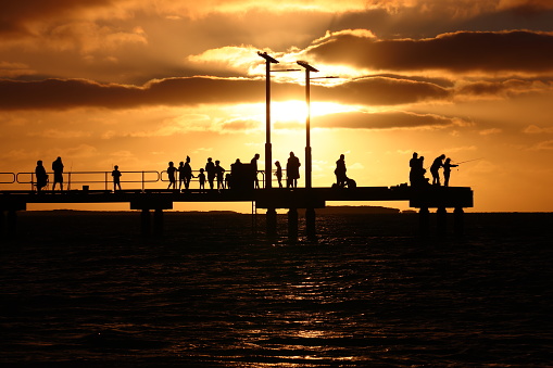 Silhouette of fishing jetty at sunset. The scene looks somewhat ominous due to the dramatic sky.