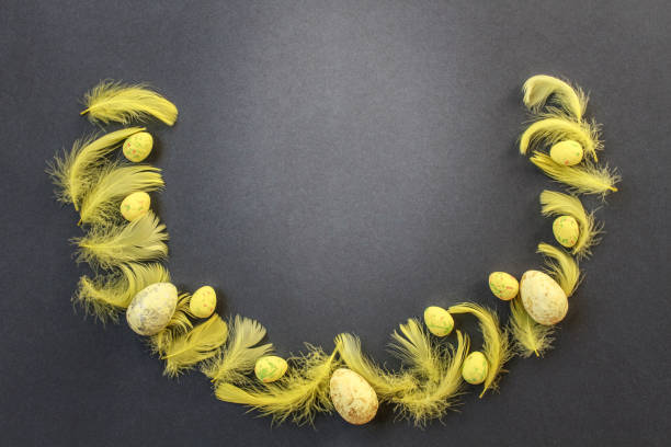 Semicircular frame of yellow Easter eggs and yellow feathers on gray blue background. Happy Easter greeting card with space for text. Easter concept. Flat lay. Copy space