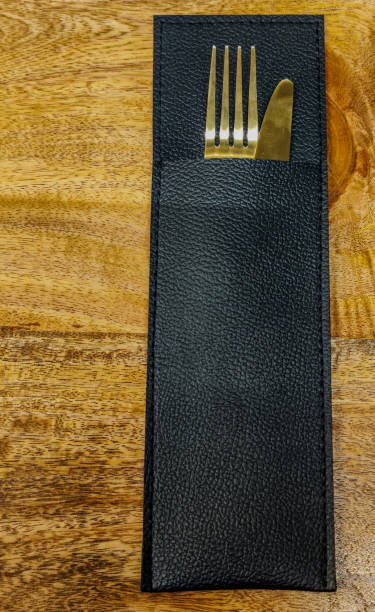 istock Gold fork and knife in a black leather case on a wooden surface. 2065664155