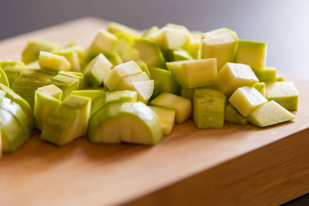 chopped zucchini into cubes on wooden board close-up