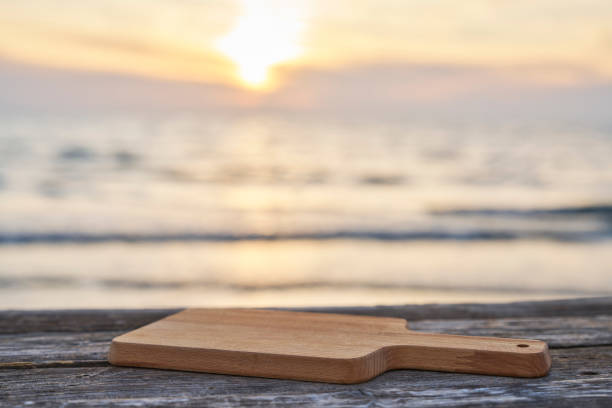 istock Empty wooden table with cutting board over summertime seaside background 2065670374