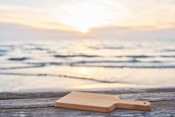 istock Empty wooden table with cutting board over summertime seaside background 2065670375