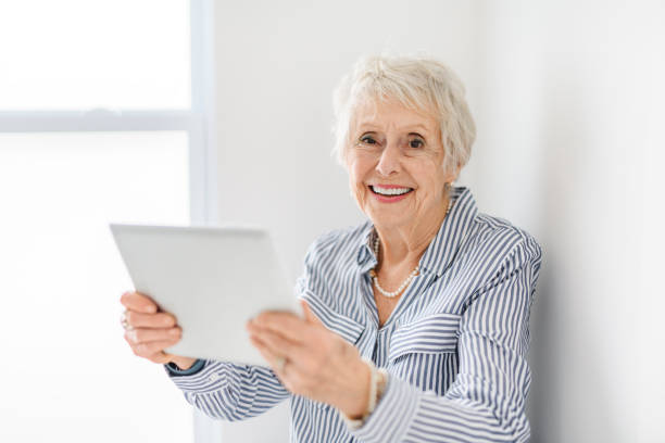 istock senior lady posing at home portrait close to a window with tablet 2065672740